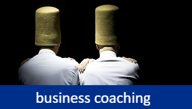 Business Coaching - zwei Menschen von hinten mit großen Filzhüten über dem Kopf